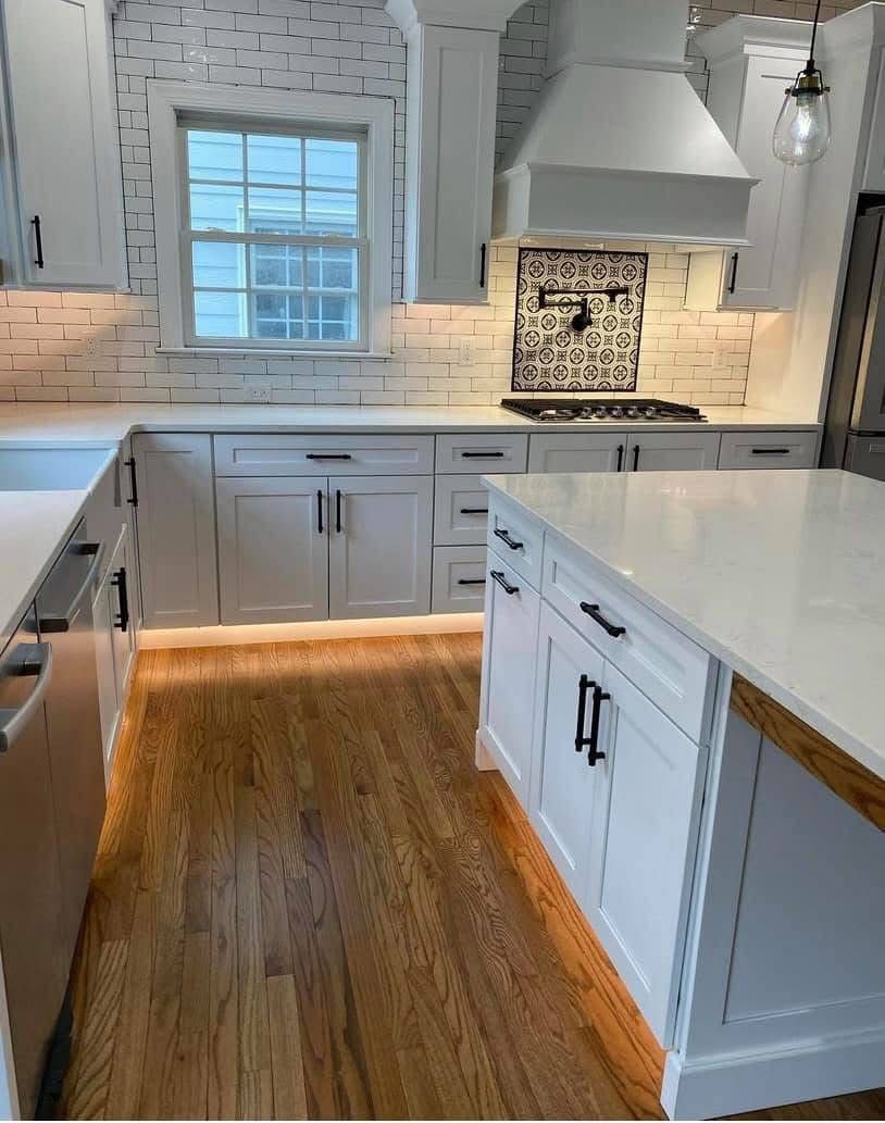 A white kitchen with under-cabinet lighting glowing along the floor