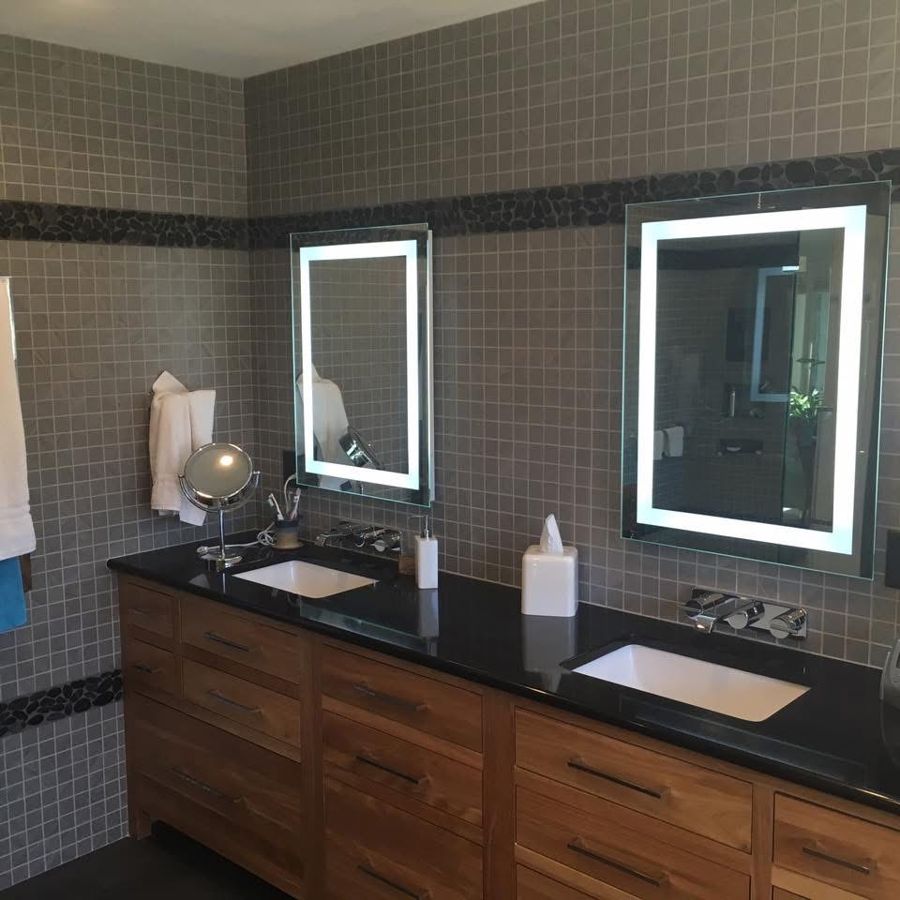 Two lighted vanity mirrors over a double sink